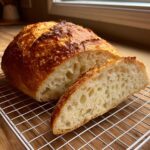 A loaf of homemade french bread, sliced open to show the airy, open crumb structure and golden crust.