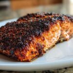 Close-up of a juicy salmon fillet with a dark, spicy crust, prepared using the blackened salmon technique.