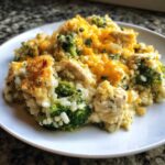 A close-up serving of creamy chicken broccoli rice casserole topped with melted cheddar cheese and crispy breadcrumbs.