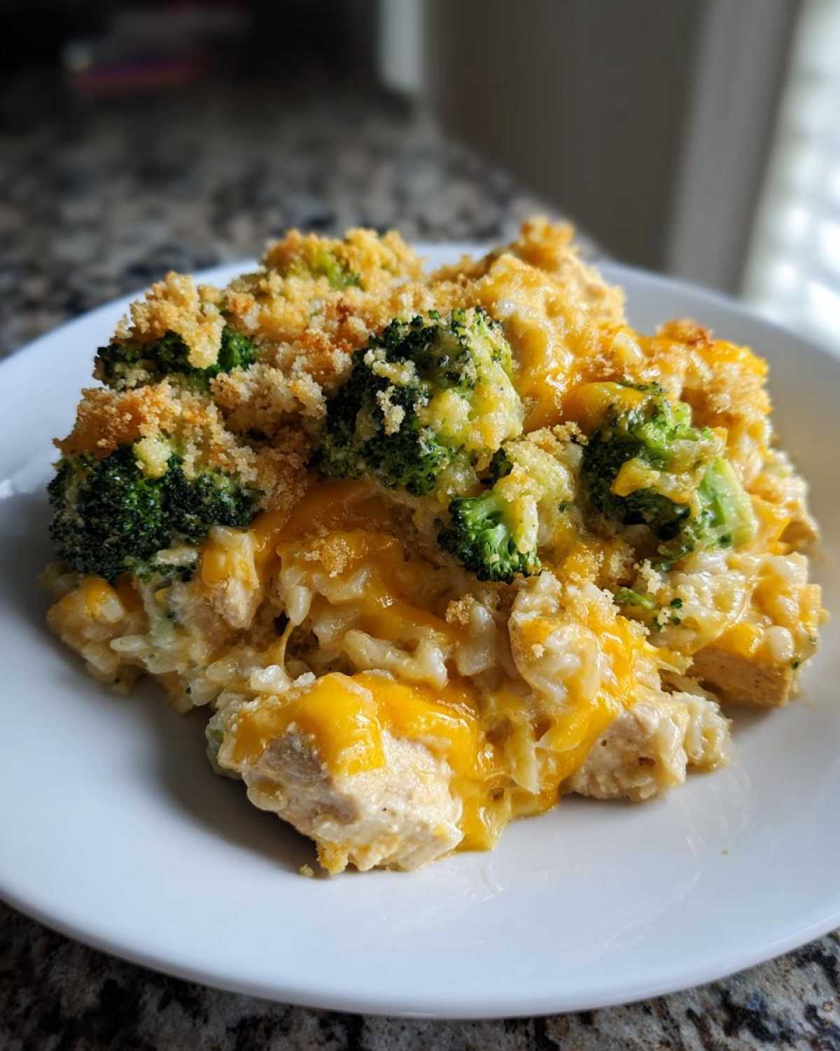 A close-up serving of cheesy chicken broccoli rice casserole topped with crunchy breadcrumbs.
