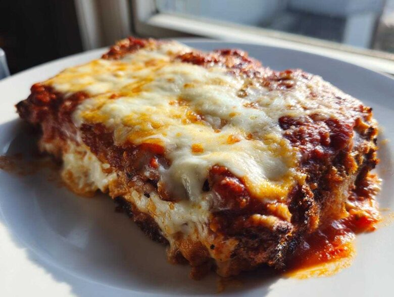 Close-up of a serving of baked chicken parmesan recipe, covered in melted mozzarella and tomato sauce.