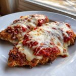 Two breaded cutlets covered in marinara sauce and melted mozzarella cheese for a delicious chicken parmesan recipe.