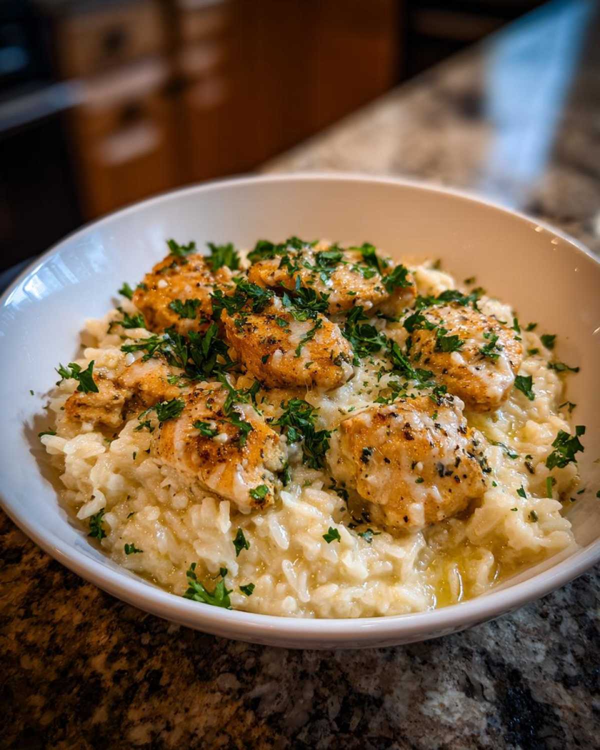 Close-up of tender chicken scampi pieces served over creamy garlic parmesan rice, garnished with fresh parsley.