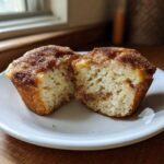 A cinnamon sugar french toast muffin cut in half on a white plate, showing the soft, light interior.