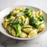 A close-up of creamy broccoli pasta featuring shell-shaped noodles, bright green broccoli florets, and grated Parmesan cheese.