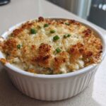 Close-up of a creamy popper dip baked in a white ramekin, featuring a golden, crunchy breadcrumb topping and green onion garnish.