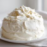 A generous mound of creamy, white vanilla buttercream frosting sitting on a white plate.