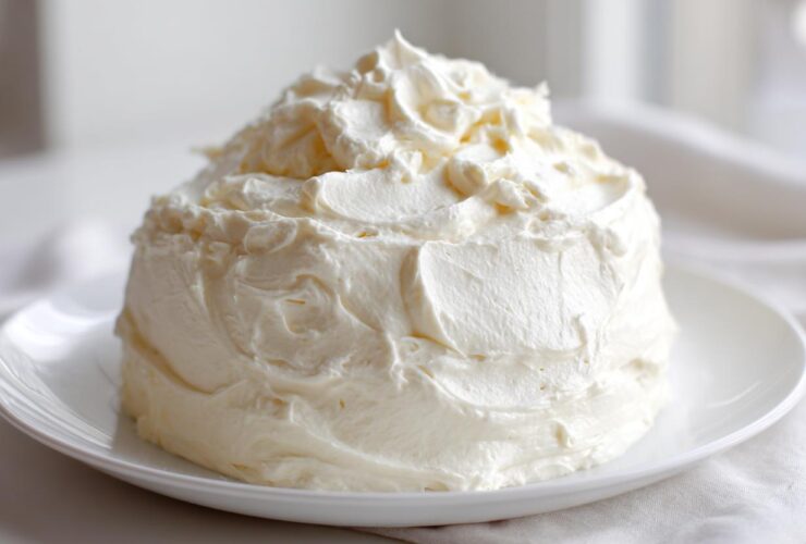 A generous mound of creamy, white vanilla buttercream frosting sitting on a white plate.