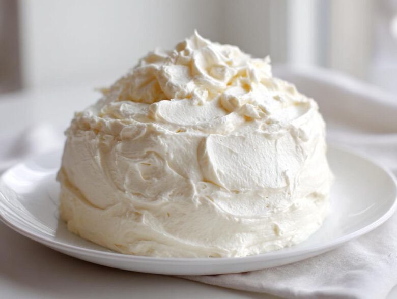 A generous mound of creamy, white vanilla buttercream frosting sitting on a white plate.