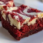 Close-up of a fudgy red velvet brownies square with a thick, white cream cheese swirl topping.