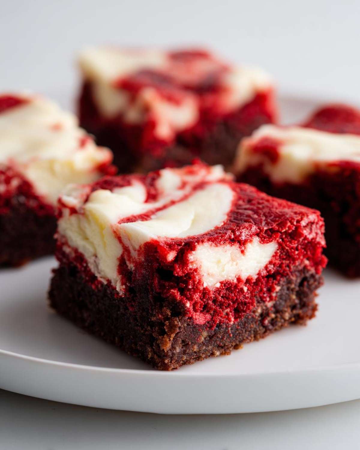 Close-up of a fudgy red velvet brownies square topped with a white cream cheese swirl.