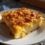 A hearty slice of funeral potatoes recipe topped with crispy, golden cornflakes, served on a white plate.