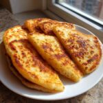 A plate stacked with freshly cooked, golden brown irish potato farls, lightly charred from the griddle.