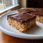 A square of lunch lady peanut butter bars featuring a thick, chewy oat base and a smooth chocolate frosting layer.