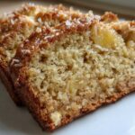 Close-up of two moist slices of hawaiian banana bread, showing the crumb texture and coconut topping.