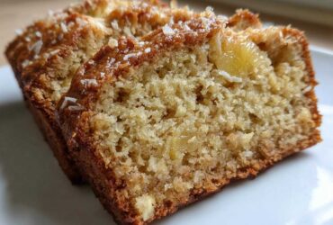 Close-up of two moist slices of hawaiian banana bread, showing the crumb texture and coconut topping.