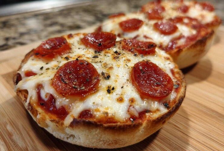 Close-up of a freshly baked pepperoni english muffin pizza topped with melted cheese and herbs.