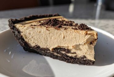 A close-up slice of amazing peanut butter pie featuring a thick, creamy filling and a dark chocolate crumb crust.