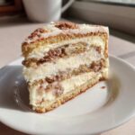 Close-up of a delicious slice of layered christmas tree cheesecake with creamy filling and nutty layers.