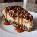 A close-up of a rich slice of turtle cheesecake topped with pecans and dripping with caramel sauce.