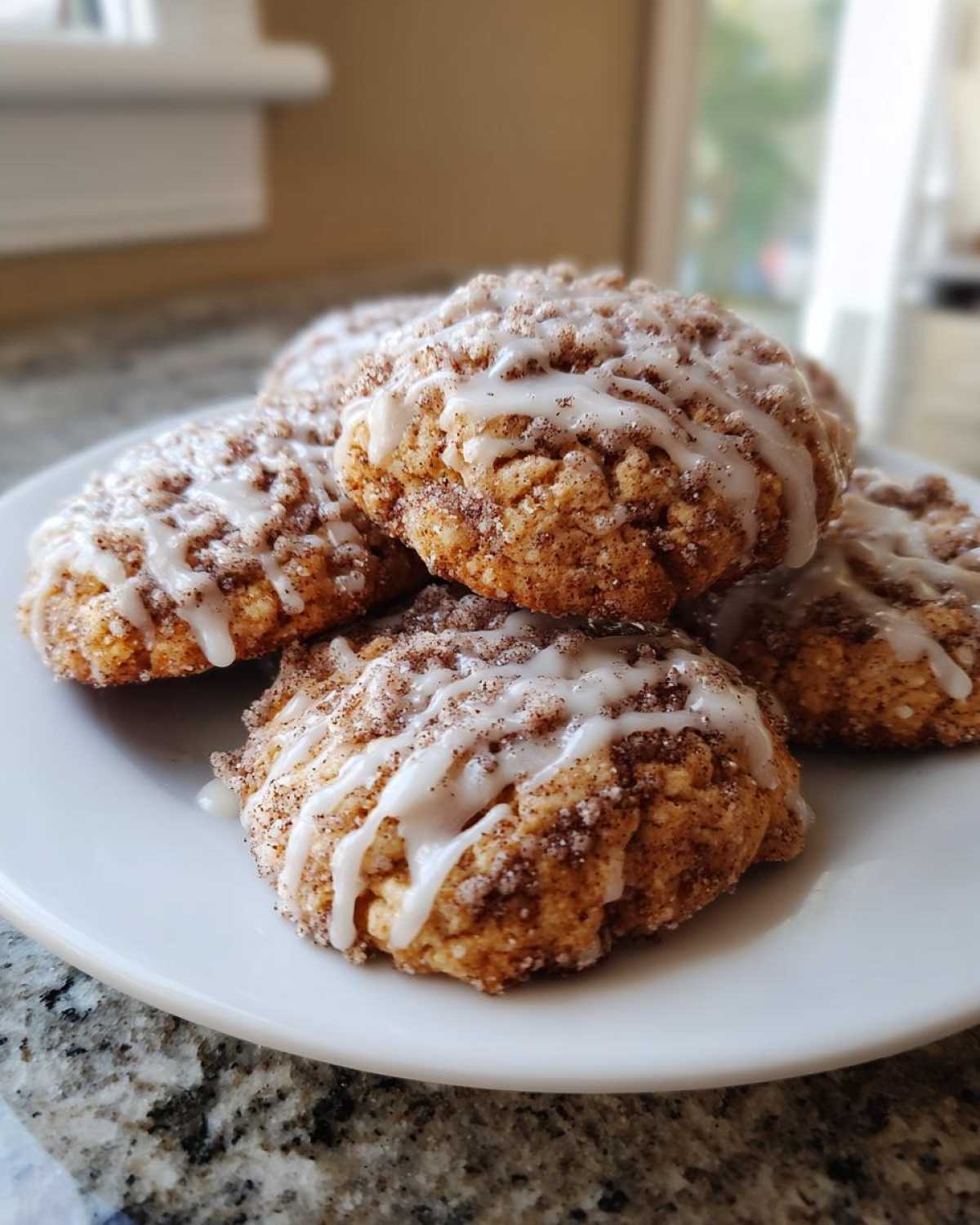 A stack of soft coffee cake cookies coated in cinnamon sugar and drizzled with white vanilla icing.