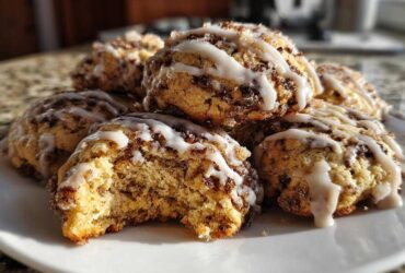 A stack of soft coffee cake cookies drizzled with white icing, one cookie has a bite taken out.