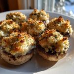 Close-up of several golden brown stuffed mushrooms recipe appetizers with a crispy breadcrumb topping on a white plate.