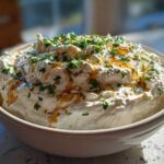 A bowl of fluffy whipped feta dip drizzled with honey and sprinkled with fresh green parsley.