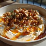 Close-up of a bowl of creamy whipped ricotta dip drizzled with honey and topped with toasted walnuts and rosemary.