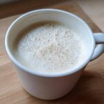 Close-up of a creamy white hot chocolate topped with foam in a white mug.