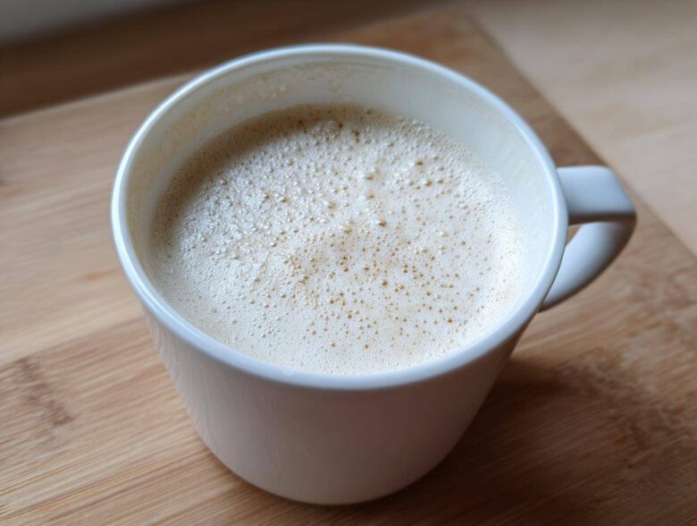 Close-up of a creamy white hot chocolate topped with foam in a white mug.