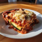 A hearty slice of zucchini lasagna layered with meat sauce and topped with bubbly melted cheese.