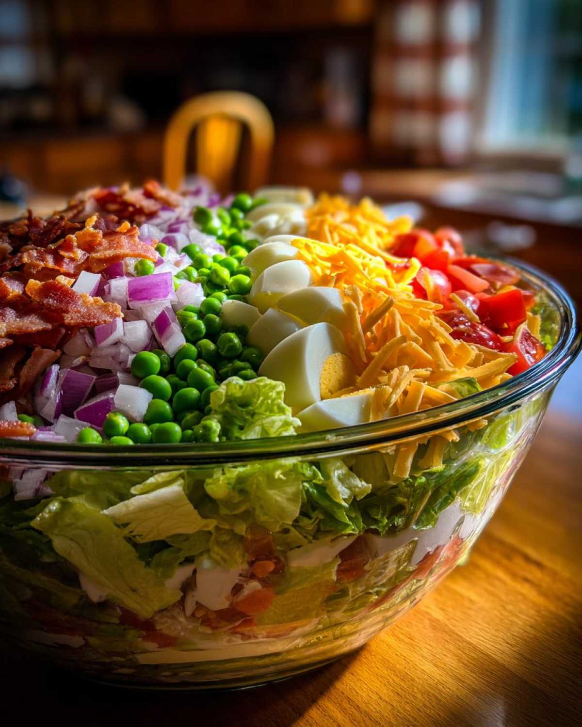 Close-up of the distinct, colorful layers of toppings on a classic 7 layer salad in a clear glass bowl.