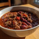 Close-up of a white bowl filled with rich, hearty chili featuring ground meat and kidney beans.