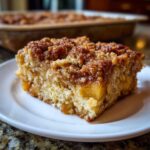 A close-up of a square slice of baked oatmeal with a thick, crunchy cinnamon streusel topping, served on a white plate.