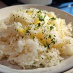 Close-up of fluffy white rice seasoned with melted butter and topped with fresh chopped parsley, showcasing the amazing butter rice flavor.