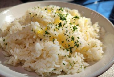 Close-up of fluffy white rice seasoned with melted butter and topped with fresh chopped parsley, showcasing the amazing butter rice flavor.