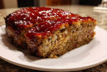 A thick slice cut from a perfectly baked meatloaf topped with a shiny, rich red glaze.