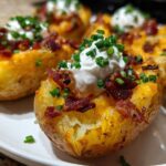 Close-up of perfectly baked potato skins loaded with melted cheese, crispy bacon bits, sour cream, and fresh chives.