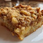 Close-up of a square slice of apple baked oatmeal topped with a cinnamon streusel crumb topping.
