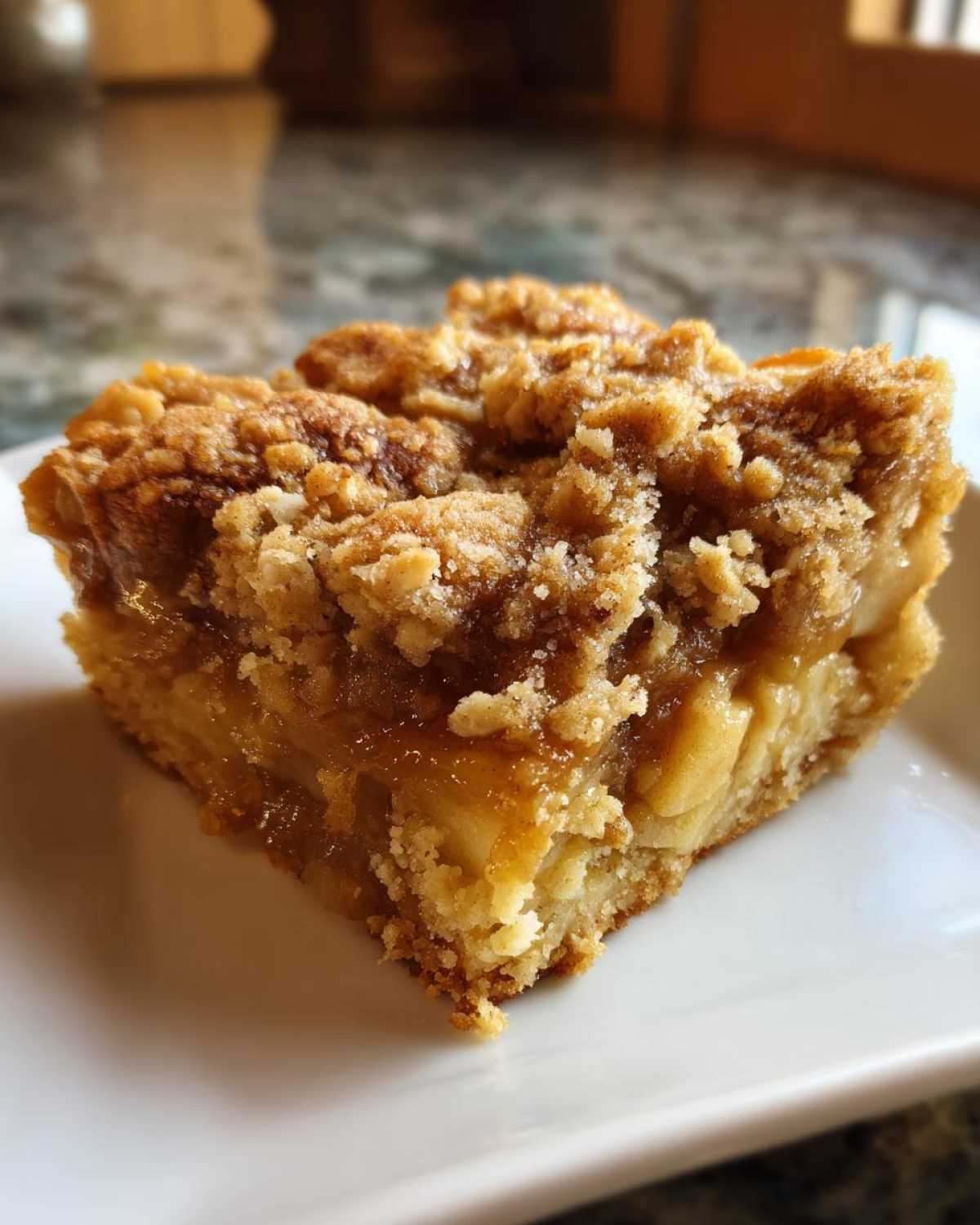 Close-up of a square slice of apple baked oatmeal with a thick, gooey fruit layer and a crunchy cinnamon crumble topping.