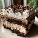 Close-up of a layered slice of Baileys Chocolate Cheesecake Trifle topped with whipped cream and chocolate shavings.