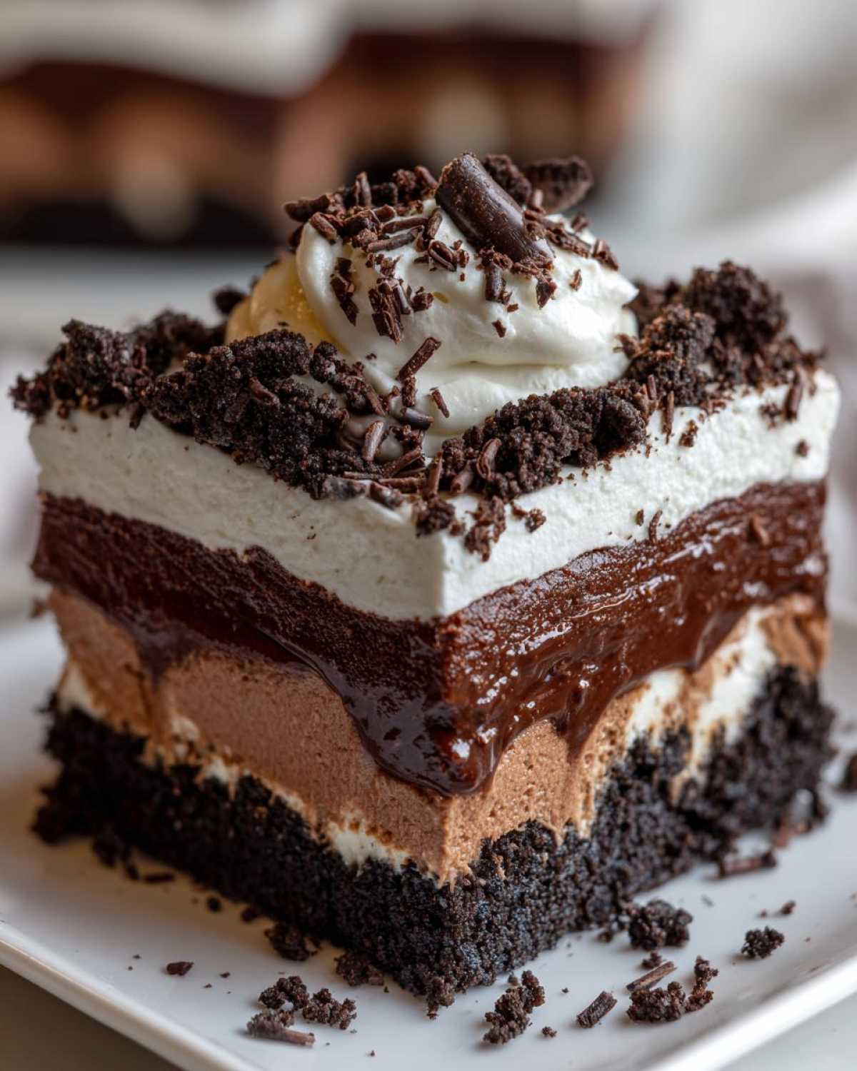 Close-up of a decadent slice of Baileys Chocolate Cheesecake Trifle showing four distinct layers topped with whipped cream and chocolate shavings.