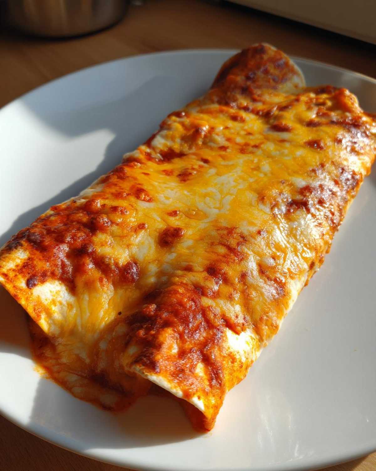 A single serving of baked cheese enchiladas covered in melted, bubbly red sauce and golden cheese.