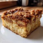 A close-up of a square slice of baked french toast with a thick, sugary cinnamon streusel topping.