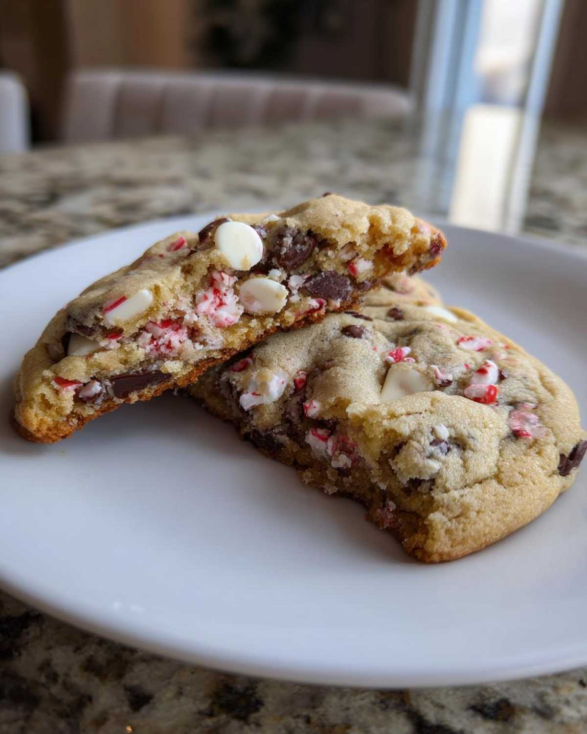 Close-up of chewy peppermint chocolate chip cookies cut in half, showing melted chocolate and crushed candy cane pieces.