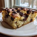 Close-up of a thick, fluffy slice of chocolate chip sheet pan pancakes served on a white plate.