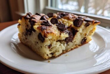 Close-up of a thick, fluffy slice of chocolate chip sheet pan pancakes served on a white plate.