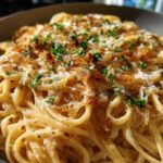 Close-up of creamy french onion pasta tossed in sauce, topped with caramelized onions, grated cheese, and fresh parsley.