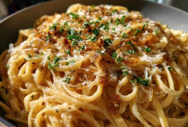 Close-up of creamy french onion pasta tossed in sauce, topped with caramelized onions, grated cheese, and fresh parsley.